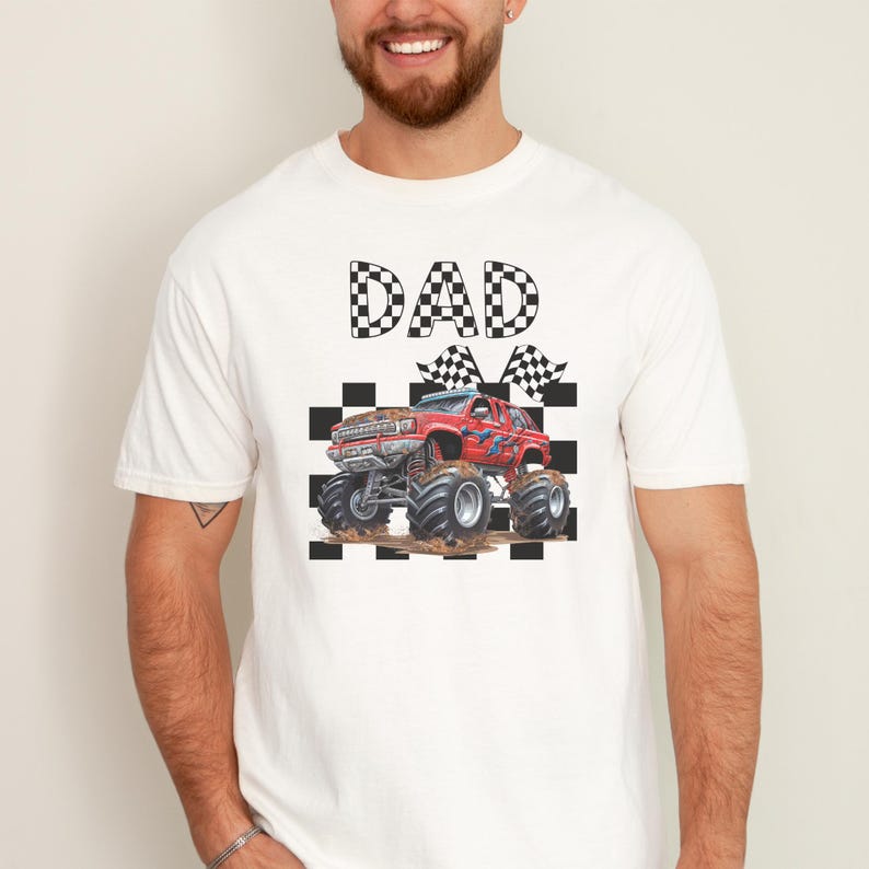 以下が含まれることがあります： 白地に黒と白の市松模様の文字で「DAD」と書かれたTシャツ。赤いモンスタートラックが市松模様の旗を持ち、市松模様の背景に描かれている。
