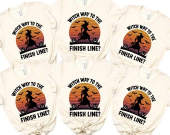 May include: Six cream-colored t-shirts with a Halloween design. Each shirt features a circular graphic with a witch silhouette, bats, pumpkins, and the text "Witch Way to the Finish Line?" in black. The graphic has an orange and yellow sunset background.