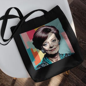 May include: Black tote bag with a colorful graphic of a woman with short, dark hair. The graphic has a pop art style with a background of pink, blue, and orange.