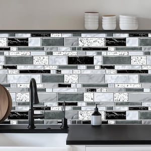 May include: A kitchen backsplash featuring a rectangular tile pattern in a mix of black, white, and gray marble textures. The tiles are arranged in a staggered brick layout with varying sizes, creating a modern, high-contrast geometric surface.