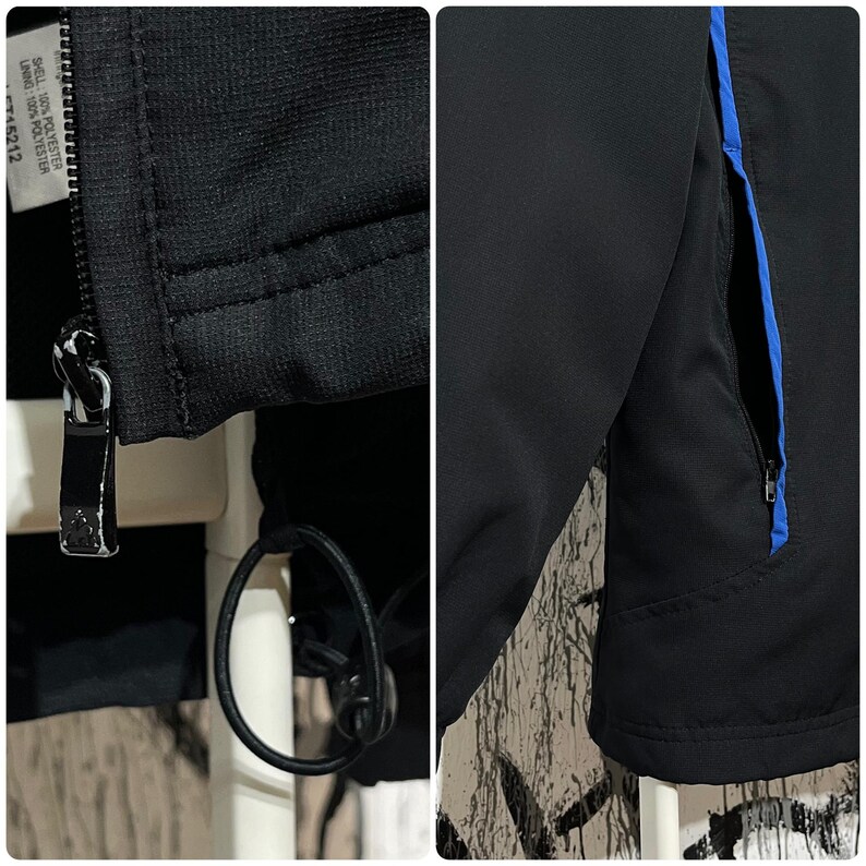 K&ouml;nnte beinhalten: Nahaufnahme einer schwarzen Jacke mit Rei&szlig;verschluss und blauem Akzent. Die Jacke hat einen schwarzen Rei&szlig;verschluss und einen Kordelzug. Das Futter ist aus 100 % Polyester.