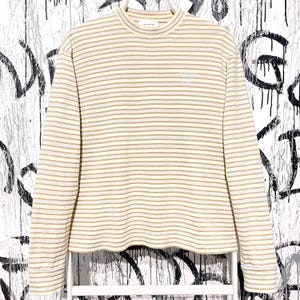 May include: A long-sleeved shirt with horizontal stripes in cream and tan. The shirt has a mock neck and the text "WHITE ROOM PALACE" is printed on the chest. The shirt is made of a soft, comfortable material.