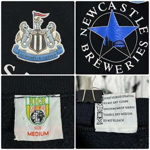 May include: Black sweatshirt featuring the Newcastle United crest and a Newcastle Breweries logo. The crest includes two seahorses and a shield. The sweatshirt has a "Kick Sportswear" tag with a "Medium" size label. Care instructions are also visible.
