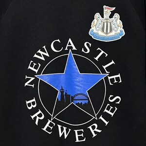 May include: Black sweatshirt featuring a blue star with a city silhouette and the words "NEWCASTLE BREWERIES" in a circle. The Newcastle United crest is at the top right.