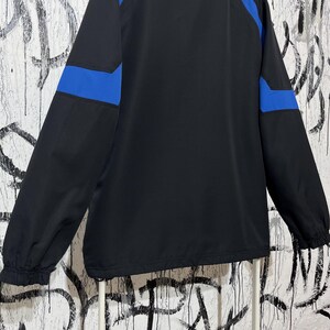 K&ouml;nnte beinhalten: Schwarze Jacke mit blauen Akzenten an den &Auml;rmeln. Die Jacke hat einen durchgehenden Rei&szlig;verschluss und einen Stehkragen. Die &Auml;rmel sind lang und haben elastische B&uuml;ndchen. Die Jacke ist aus leichtem Material.