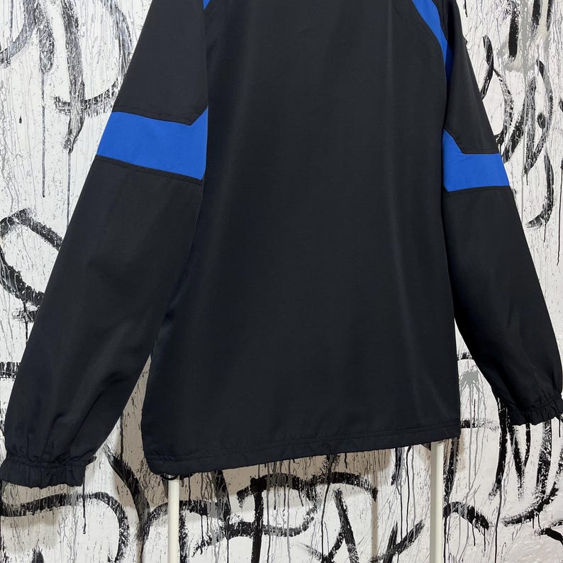 K&ouml;nnte beinhalten: Schwarze Jacke mit blauen Akzenten an den &Auml;rmeln. Die Jacke hat einen durchgehenden Rei&szlig;verschluss und einen Stehkragen. Die &Auml;rmel sind lang und haben elastische B&uuml;ndchen. Die Jacke ist aus leichtem Material.
