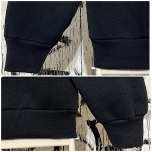 May include: Close-up of a black sweatshirt with ribbed cuffs and hem. The fabric appears to be a soft, medium-weight material. The image is a composite of four different views of the garment's sleeves and lower hem.