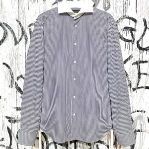 Könnte beinhalten: Ein langärmeliges Hemd mit vertikalen marineblauen und weißen Streifen. Das Hemd hat einen weißen Kragen und Manschetten sowie ein klassisches Knopfdesign. Das Hemd ist aus leichtem Stoff gefertigt.