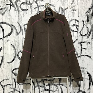 Puede incluir: Una chaqueta de forro polar marrón con cierre de cremallera y detalles en rosa. La chaqueta tiene un cuello alto y un logotipo en el lado izquierdo del pecho.