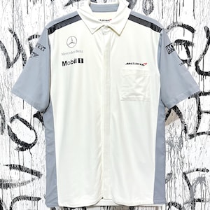 Könnte beinhalten: Weißes und graues kurzärmeliges Button-up-Shirt mit schwarzen Akzenten. Mit dem Mercedes-Benz-Logo, dem Text Mobil 1 und dem McLaren-Branding. Enthält eine Brusttasche und einen Kragen. Das Shirt hat ein sportliches Design.