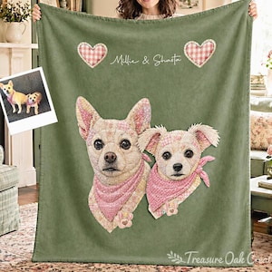Könnte beinhalten: Eine salbeigrüne Fleecedecke mit einem individuellen Porträt von zwei Hunden, die gemusterte rosa Halstücher tragen. Das Design enthält zwei rosa karierte Herzen und den Text Millie & Shasta. Ein kleines Foto der Hunde ist befestigt.