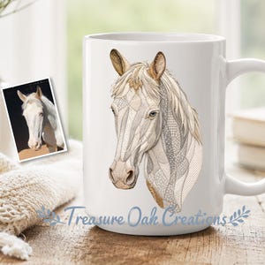 May include: White ceramic mug featuring a detailed illustration of a horse's head. The horse has a light-colored mane and a patchwork-style design. The mug has a large handle and the text "Treasure Oak Creations" is printed on the bottom.