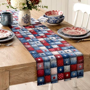 May include: A wooden dining table is set with a patriotic theme. A red, white, and blue patterned table runner with stars and squares runs down the center. Dishes, bowls, and a mug are arranged around a vase of flowers.