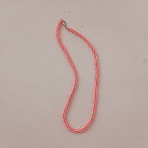 May include: A pink and green beaded necklace with a silver clasp.