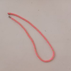 May include: A pink and green beaded necklace with a silver clasp.