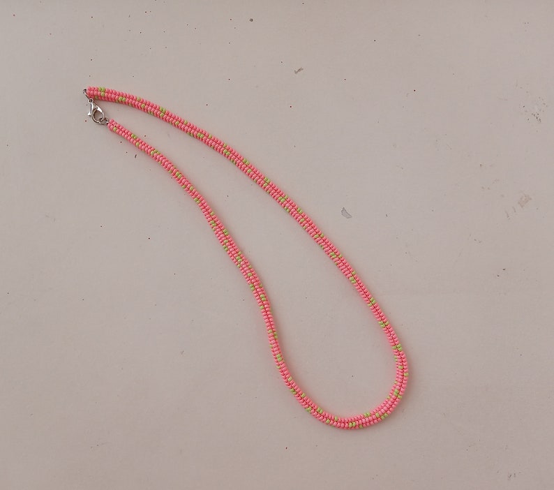 May include: A pink and green beaded necklace with a silver clasp.
