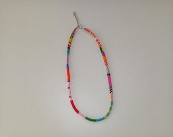 May include: A colorful beaded necklace with a silver-toned clasp. The necklace features a variety of colors, including red, pink, green, blue, yellow, and orange. The beads are arranged in a pattern, creating a vibrant and eye-catching accessory.