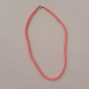 May include: A pink and green beaded necklace with a silver clasp.