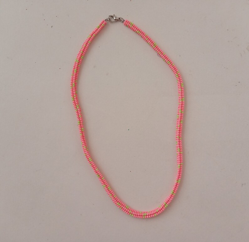 May include: A pink and green beaded necklace with a silver clasp.