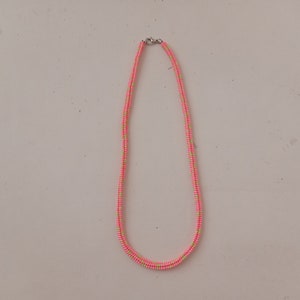 May include: A pink and green beaded necklace with a silver clasp.