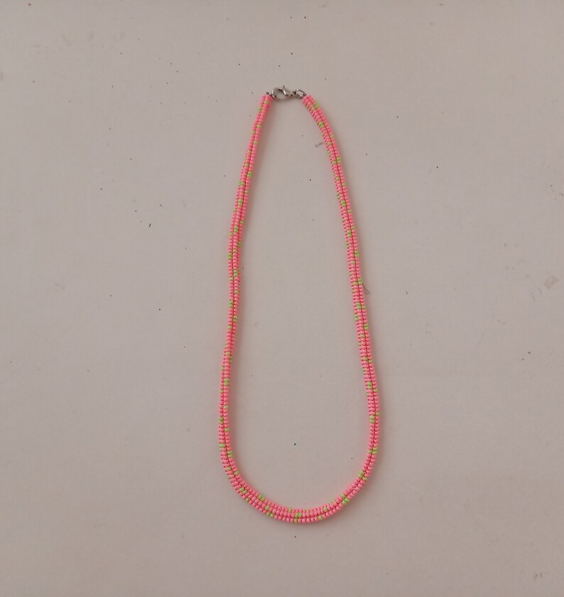 May include: A pink and green beaded necklace with a silver clasp.