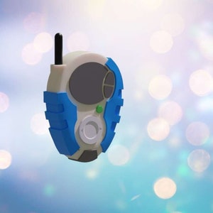 May include: A blue and white handheld device with a black antenna, a gray screen, and a green button. The device has a circular button with arrows on it.