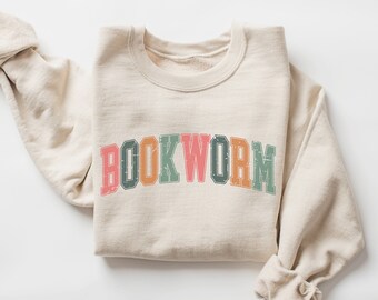 May include: A beige sweatshirt with the word "BOOKWORM" printed in colorful, retro-style letters.
