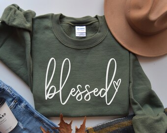 May include: A green sweatshirt with the word "blessed" written in white cursive with a small heart at the end.