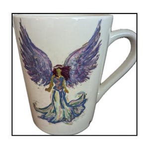 May include: White ceramic mug with a hand-painted design of an angel with purple wings and a flowing gown. The angel is depicted with a purple, blue, and green color scheme.
