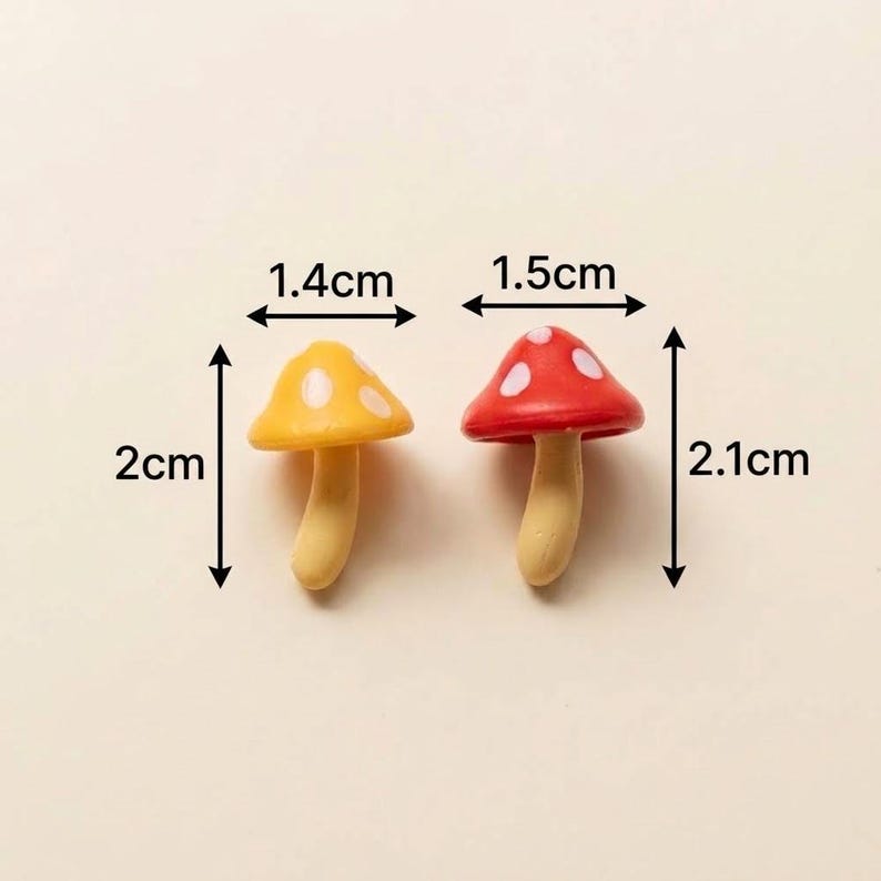 May include: Two miniature mushroom figurines with light beige stems and spotted caps. The yellow mushroom measures 1.4 cm wide by 2 cm tall. The red mushroom measures 1.5 cm wide by 2.1 cm tall. Both feature white spots on their rounded caps.
