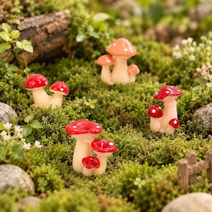 May include: A collection of miniature mushroom figurines featuring clusters of red and orange caps with white spots on light beige stems. The set includes four distinct groupings of fungi arranged across a textured green mossy surface.