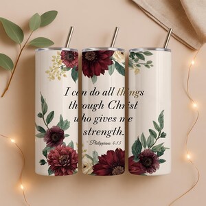 May include: Three white insulated tumblers with floral designs and silver straws. The tumblers feature burgundy and cream-colored flowers with green leaves. Text on the center tumbler reads, "I can do all things through Christ who gives me strength."