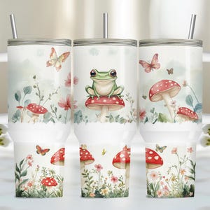 May include: Three stainless steel tumblers with a white background and a whimsical forest scene. The tumblers feature a green frog sitting on a red mushroom, butterflies, and other floral elements.