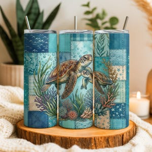May include: Three stainless steel insulated tumblers with a sea turtle design. The tumblers feature a patchwork pattern in shades of blue and teal, with a detailed illustration of sea turtles, coral, and seaweed.