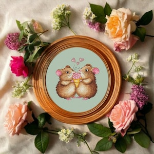 Puede incluir: Dos ratones marrones compartiendo un cono de helado con helado rosa. Los ratones están rodeados de corazones rosas sobre un fondo azul claro. La imagen está enmarcada en un marco de madera marrón.