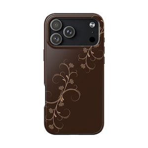 May include: A brown phone case with a floral design. The case has a glossy finish and features a detailed pattern of swirling vines and leaves in a lighter brown color. The phone case has three camera lenses.