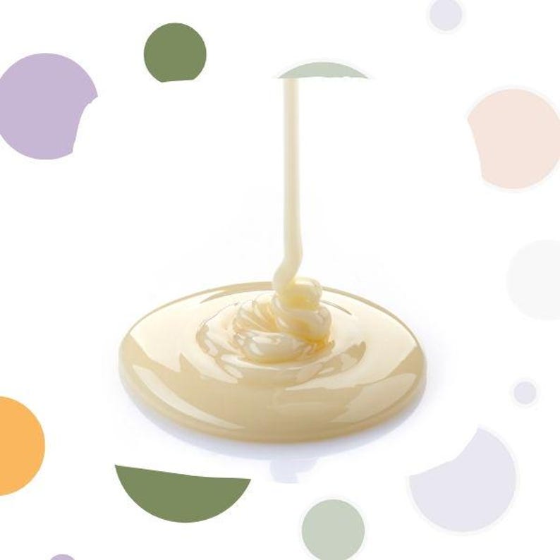 May include: A stream of creamy, off-white liquid pouring onto a pool of the same substance. The liquid forms a swirl pattern as it pools, set against a white background with colorful abstract shapes.