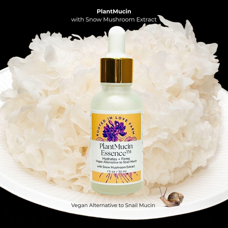 May include: A skincare product bottle labeled "Plant Mucin Essence" with a dropper, set against a backdrop of white snow mushroom. The bottle has a gold cap and a label with purple floral graphics. The text reads "Vegan Alternative to Snail Mucin". A snail is in the lower right corner.