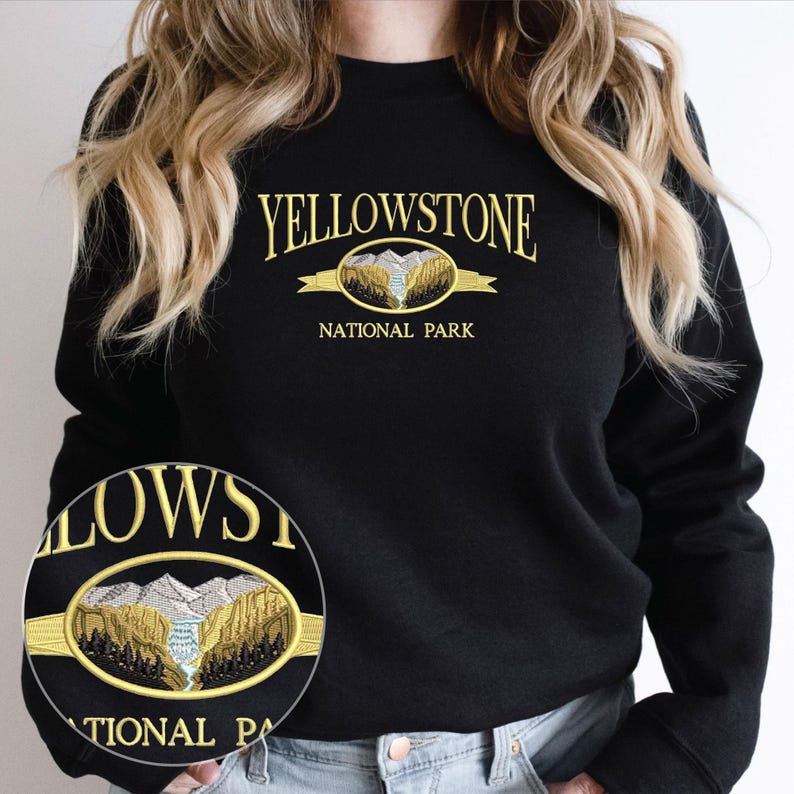 May include: Black sweatshirt with the text "YELLOWSTONE NATIONAL PARK" in gold lettering. The design includes an oval emblem with a mountain and river scene. The sweatshirt is a crew neck style.