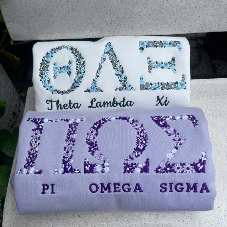 Pu&ograve; includere: Due felpe, una bianca e una lavanda, con lettere greche ricamate e disegni floreali. La felpa bianca presenta le lettere &Theta;&Lambda;&Xi; con "Theta Lambda Xi" sotto. La felpa lavanda ha &Pi;&Omega;&Sigma; con "Pi Omega Sigma" sotto.