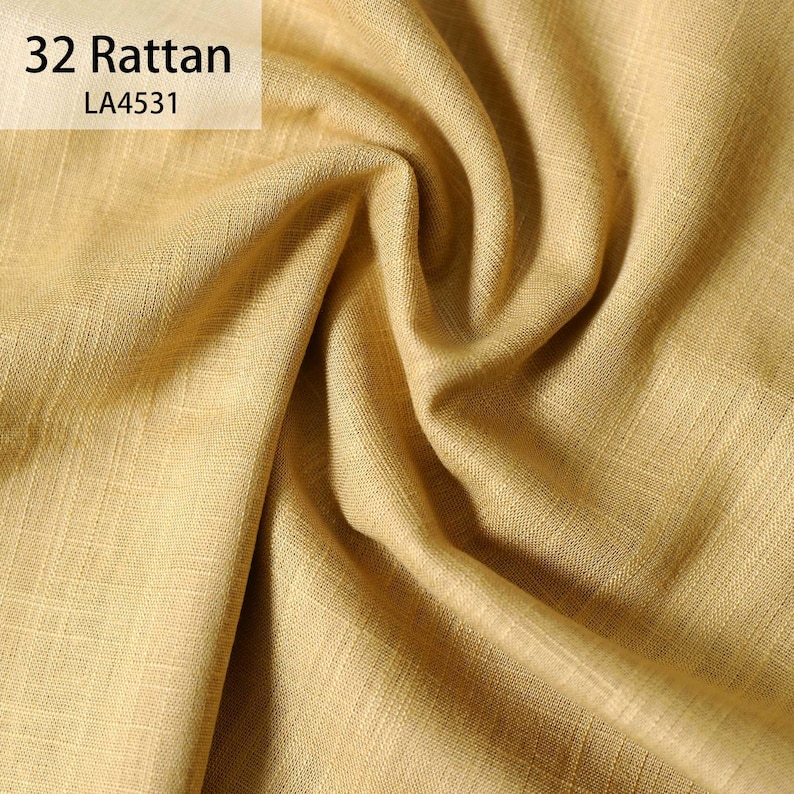 Puede incluir: Primer plano de una tela texturizada de color amarillo dorado con patrones de tejido visibles. La tela est&aacute; drapeada en pliegues suaves, creando sombras y reflejos. El texto "32 Rattan" y "LA4531" est&aacute; en la esquina superior izquierda.