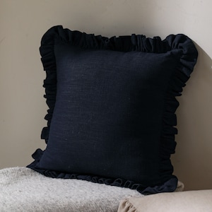 May include: A navy blue cushion with a ruffled edge. The cushion is made of a soft, textured fabric.