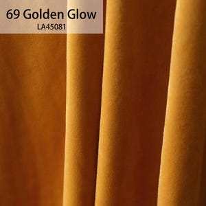 May include: Close-up of a fabric swatch in a rich golden yellow color. The fabric has a soft, velvety texture. The text "69 Golden Glow LA45081" is visible in the top left corner.