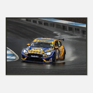 Puede incluir: Un coche de carreras amarillo y azul con el número 116 en el lateral, conduciendo por una pista mojada. El coche está patrocinado por NAPA Auto Parts y Kwik Fit.