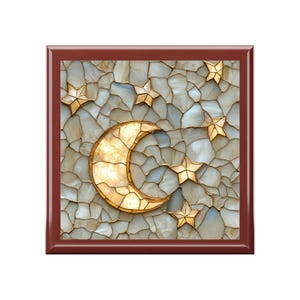 May include: A square decorative piece featuring a crescent moon and stars design. The moon and stars are gold-colored, set against a mosaic background of white, gray, and beige stones. The frame is a dark brown color.