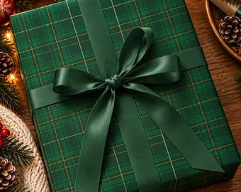 May include: A square gift box wrapped in dark green paper with a thin gold plaid pattern. The box is tied with a wide, smooth, dark green satin ribbon that forms a large, centered bow with long, flowing tails extending across the top.