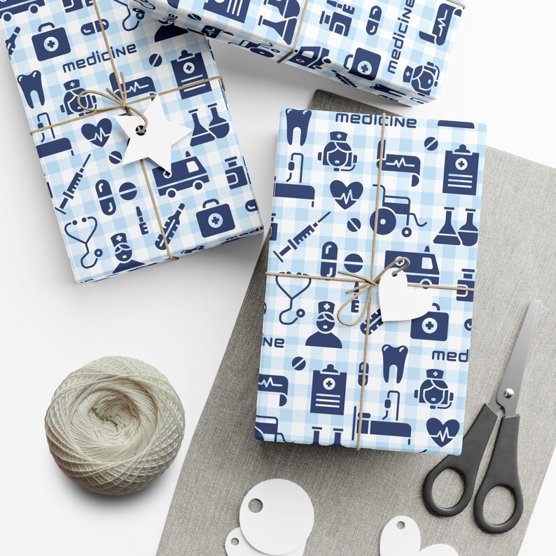 Blue and white wrapping paper with a medical theme. The paper features a variety of medical symbols, including a stethoscope, a syringe, a pill bottle, a thermometer, and a first aid kit. The paper also includes the word "medicine" repeated throughout.
