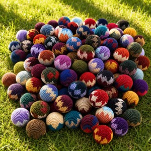 May include: A large collection of small, round, crocheted balls featuring various multi-colored geometric patterns. Each sphere is crafted with intricate yarn stitching, displaying a wide array of vibrant hues including red, blue, yellow, purple, and green, arranged in distinct zigzag and block designs.