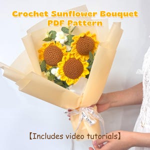 May include: A crochet sunflower bouquet wrapped in tan paper, tied with a white ribbon. The bouquet features three sunflowers with yellow petals and brown centres, along with white and green accents. Text on the image reads "Crochet Sunflower Bouquet PDF Pattern" and "Includes video tutorials".