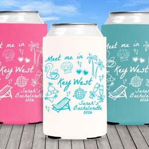 May include: Three beverage can coolers in pink, white, and teal, each with a white doodle design. The design includes a swan, seashell, palm trees, and the text "Meet me in Key West" and "Sarah's Bachelorette 2026".